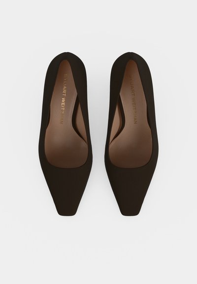 Paire de chaussures plates Stuart Weitzman marron foncé à bout pointu, vues de dessus sur un fond clair.
