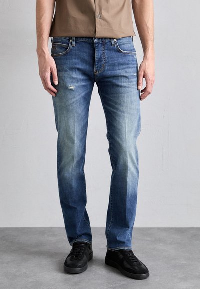 Jeans din denim de un albastru deschis, cu detalii deteriorate, croi drept, talie medie și o ușoară decolorare. Asortați cu adidași negri.