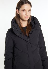 Schwarze, gesteppte Pufferjacke mit hohem Kragen, Frontreißverschluss und Druckknöpfen. Verfügt über seitliche Taschen und ein elegantes Nahtmuster.
