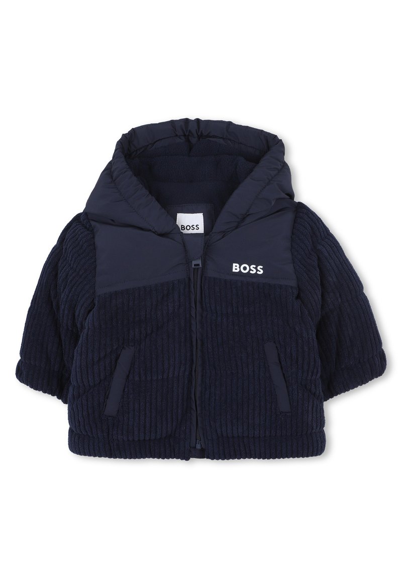 Veste matelassée bleu marine avec capuche, présentant une texture côtelée, une fermeture éclair à l'avant et un logo sur la poitrine et les épaules ; comprend des poches latérales.