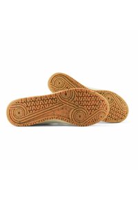 Sneakersohlen aus Gummi mit einem strukturierten orangefarbenen Muster, das kreisförmige und wellenförmige Designs aufweist, ergänzt durch Farbspritzer.