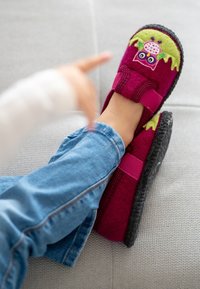 Lila Filzpantoffeln mit grünem Eulendesign und pinken Akzenten, ausgestattet mit einer strukturierten schwarzen Sohle und einem verstellbaren Riemen für einen sicheren Sitz.