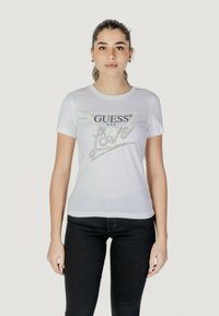 Witte katoenen t-shirt met het "GUESS® U.S.A." logo in zwart en zilver, voorzien van een sprankelend "Love" ontwerp. Ronde hals en korte mouwen.