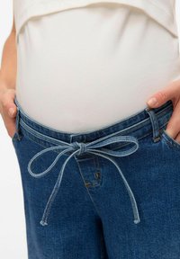 Niebieskie dżinsowe spodnie ciążowe z elastycznym paskiem i luźnym krojem, charakteryzujące się gładką fakturą i subtelnymi przeszyciami.