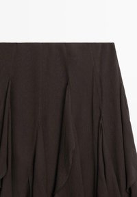 Bruine geplooide rok met een gestructureerd oppervlak, voorzien van gedrapeerde stof die beweging en vloeiendheid creëert. De zoom eindigt in zachte rondingen.