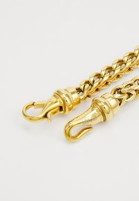 Goldfarbene Metallkette mit einem dicken, ineinandergreifenden Design, zwei Verschluss-Haken an jedem Ende und glatten, glänzenden Oberflächen.