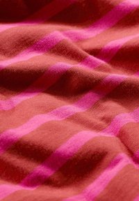 Textil med horisontella ränder i djup röd och klar rosa, med en mjuk, strukturerad yta och lätta rynkor som skapar djup.