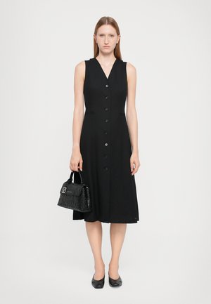 Black sleeveless dress with a V-neck, button-down front, and side pockets. Paired with a black structured handbag featuring a textured pattern.
