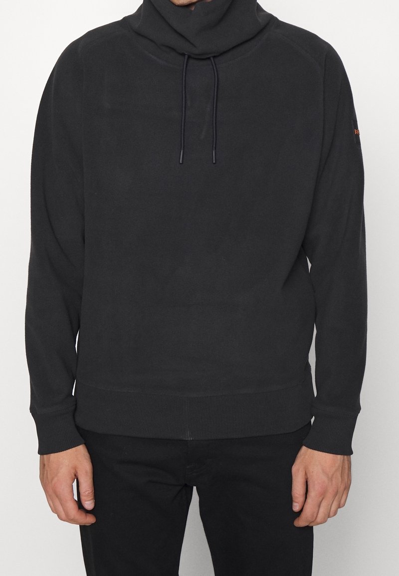 Sudadera negra con cuello alto, detalles de cordón y puños y dobladillo acanalados. Tela suave con un ajuste relajado.