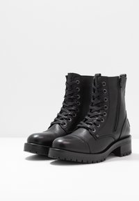 Zwarte leren enkellaarsjes met een gestructureerde afwerking, voorzien van veters aan de voorkant, een ritssluiting aan de zijkant en een stevige hak met een robuuste zool.