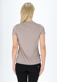 Kortærmet, tætsiddende t-shirt i lys brun, lavet af blødt stof. Har en simpel rund halsudskæring og subtile syninger.