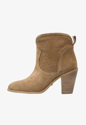 Bottine en daim marron avec un design perforé, bout pointu et un talon empilé. Finition sans couture avec une languette au dos pour un enfilage facile.