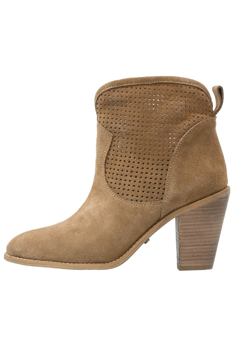 Stivale alla caviglia in suede marrone con design perforato, punta affilata e tacco impilato. Finitura senza giunture con una linguetta sul retro per indossarlo facilmente.