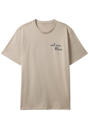 Béžové tričko s krátkym rukávom a okrúhlym výstrihom s textom "calvin klein" vytlačeným kurzívou na ľavej strane hrudníka.