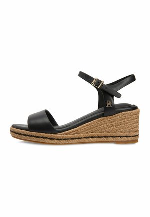 Sandalia cuña de cuero negro con correa en el tobillo, hebilla dorada y plataforma de yute trenzado.