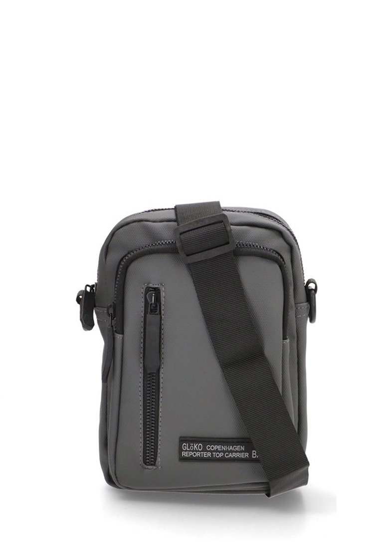 Bolso de hombro gris hecho de tela duradera; cuenta con un bolsillo frontal con cremallera, correa ajustable y parche con logo. Diseño rectangular compacto.