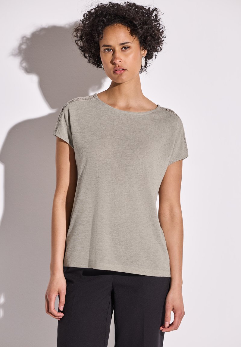 Šedé tričko s krátkým rukávem, volnějšího střihu a kulatým výstřihem. Obsahuje texturované detaily na ramenou a měkkou, lehkou tkaninu.