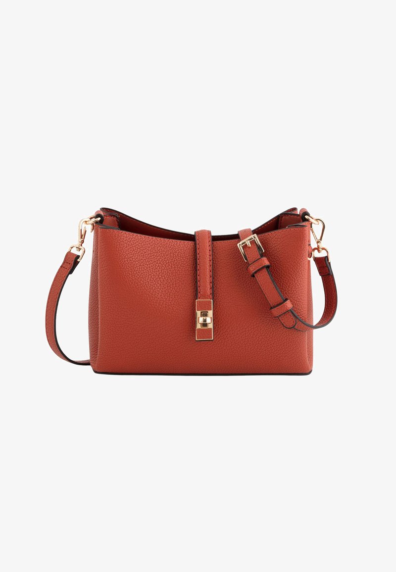 Torba na ramię z rustykalnej, ziarnistej skóry w kolorze rdzy, z regulowanym paskiem oraz złotym klamrą i zapięciem na obrót, na białym tle.