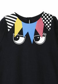 Vestido negro con acentos triangulares de colores en amarillo, azul y rojo, con patrones a rayas y de lunares en los hombros.