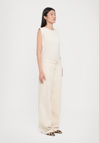 Beige sleeveless top, wide beige trousers, and leopard-print pointy shoes. Soft fabric with relaxed fit, smooth texture, and simple design.