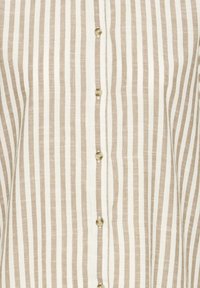 Chemise beige et blanche à rayures verticales avec de petits boutons ronds beiges sur le devant au centre.