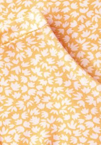 Tejido amarillo con un patrón floral blanco, con pequeñas formas parecidas a hojas. La textura parece suave con un acabado blando.