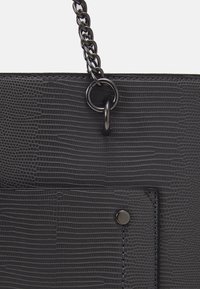 Czarna torebka z sztucznej skóry z teksturowanym wzorem węża, łańcuszkowym uchwytem i metalowym zapięciem z przodu kieszeni.