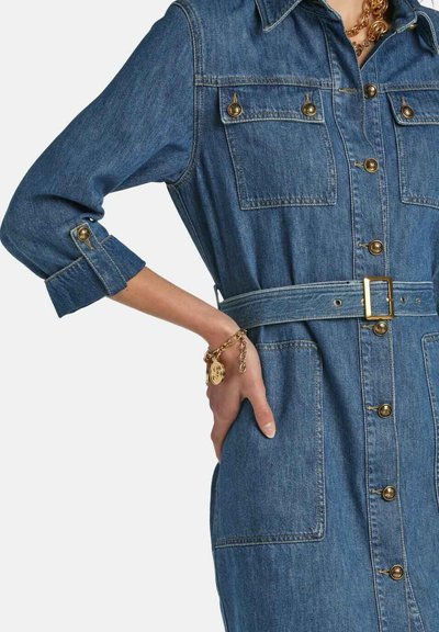 Denimkjole med krave, guldknapper, forlommer og bælte i taljen. Farven er middelblå med et klassisk design.