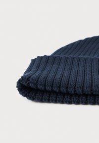 Gorro de punto en azul marino oscuro con textura acanalada, borde doblado y un acabado suave, mostrando un primer plano de los detalles de la tela.