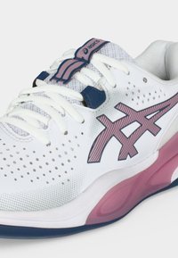 Λευκό αθλητικό παπούτσι Asics με ροζ και ναυτικό μπλε λογότυπο, λευκά κορδόνια, διάτρητο επάνω μέρος και ροζ λεπτομέρεια με μαξιλαράκι στη σόλα.
