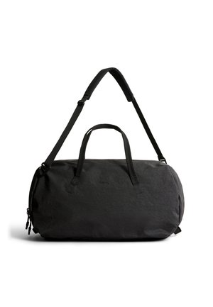 Sac de sport en tissu noir doux avec deux poignées et une bandoulière rembourrée réglable, présenté sur un fond blanc.