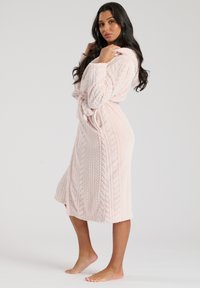 Robe lungo con cappuccio di un delicato rosa, realizzato in un morbido tessuto testurizzato con motivo a treccia, dotato di cintura da annodare e tasche laterali.