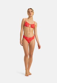 Rode bikini met stippen en dunne bandjes, met een sleutelgatontwerp aan de bovenkant en gerimpelde details op de hoge taille broekjes. Zachte textuur.