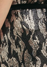 Svart paljettyg med ett virvlande mönster i guld- och roséguldstoner, med en slät textur och en lätt glans.