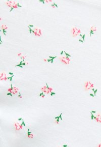 Λευκό ύφασμα με μικρά, διάσπαρτα ροζ ανθικά σχέδια που περιλαμβάνουν πράσινους μίσχους και φύλλα σε ένα λεπτό επαναλαμβανόμενο μοτίβο.