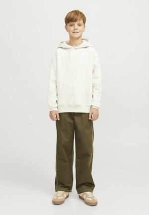 Sudadera blanca con capucha y bolsillo delantero, combinada con pantalones de pierna ancha en verde oliva y zapatillas beige con un diseño ligero.