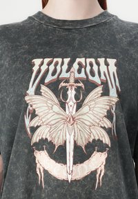 Schwarzes grafisches T-Shirt mit einem großen, aufwändigen Design, das ein Schwert und einen Schmetterling zeigt, akzentuiert in hellen Rosa- und Blautönen, mit einer Vintage-Textur.