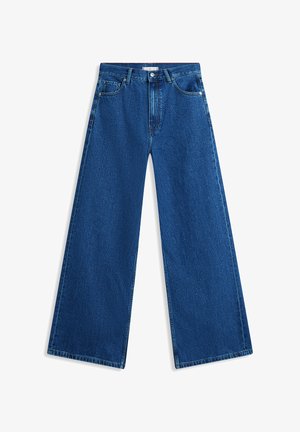 Laineliste säärega laiad sinised teksapüksid, millel on kõrge vöökoht ja klassikaline viie taskuga disain. Kangas on tekstuurse viimistlusega ja kergelt pleekinud.