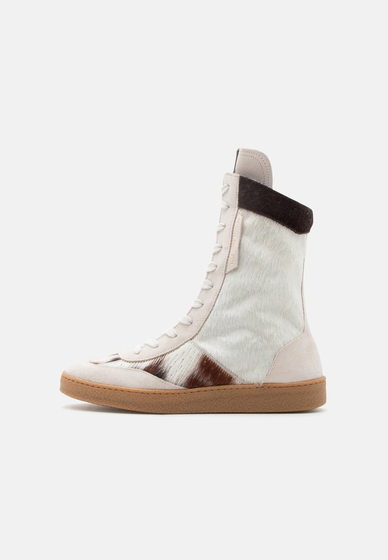 Ψηλό αθλητικό παπούτσι με λευκά και καφέ γούνινα τμήματα, λευκά κορδόνια, σκούρο καφέ γιακά και ανοιχτό καφέ ελαστική σόλα.