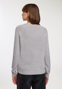 Szary dziergany sweter z okrągłym dekoltem i prążkowanymi mankietami, prezentujący teksturowane wykończenie oraz projekt rękawów raglanowych.