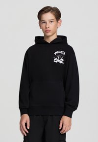 Felpa nera in pile con tasca a marsupio frontale, polsini e orlo a costine, con logo grafico bianco di un orso sul lato sinistro del petto.