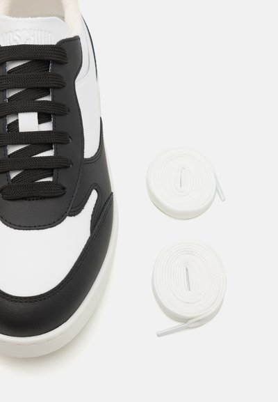 Black and white sneaker made of smooth leather, featuring black laces and a cushioned sole. Includes two white, round shoelaces.