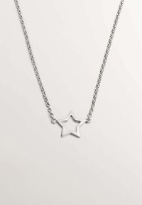 Collar de plata con un colgante de estrella que presenta un centro hueco. La cadena es de eslabones, y el diseño general es elegante y minimalista.