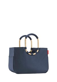 Sac cabas bleu marine en tissu texturé, doté de deux poignées circulaires en métal doré et d'une poche latérale. Étiquette logo rouge sur un côté.