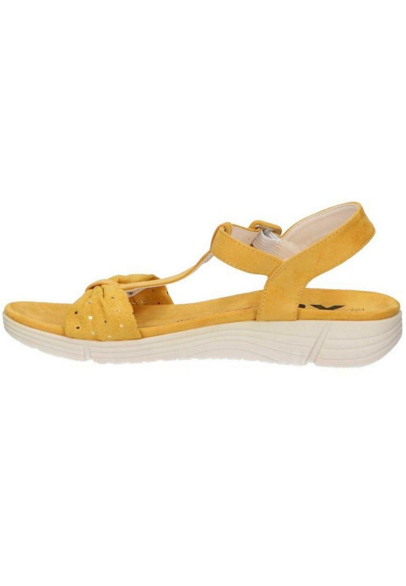 Sandalo in suede giallo con fronte annodato, cinturino regolabile e suola bianca texturizzata. Presenta perforazioni per un dettaglio aggiuntivo.