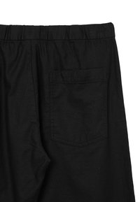 Schwarze Hose mit elastischem Bund und einer einzigen Gesäßtasche, aus strukturiertem Stoff, der ein einfaches und funktionales Design zeigt.