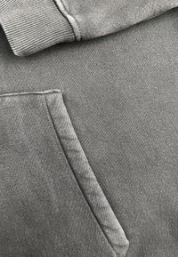 Grijze sweatshirtstof met een geribbelde manchette aan de bovenkant, voorzien van een zijzak en een zachte, gladde textuur over het hele lichaam.