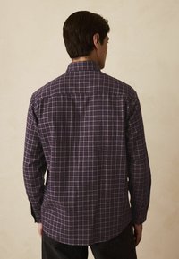 Firkantet langærmet skjorte i lilla og hvid, med knapnederede krave og lige kant. Bomuldsstof med en blød tekstur.