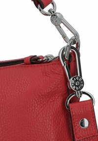 Borsa a tracolla in pelle rossa con superficie texturizzata, caratterizzata da una chiusura in metallo argentato e accessori, tracolla regolabile e chiusura con cerniera.