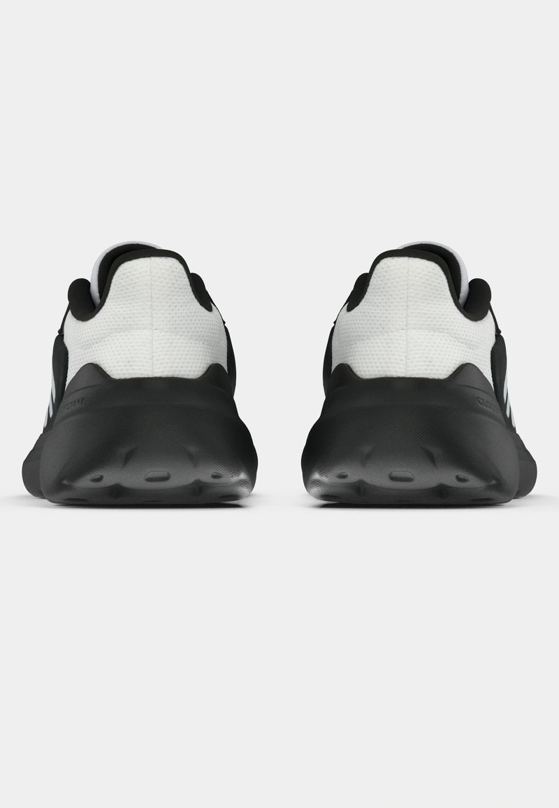 Zapatillas deportivas en blanco y negro con un upper texturizado, suela negra lisa y tacones redondeados, que cuentan con una lengüeta trasera y un branding minimalista.